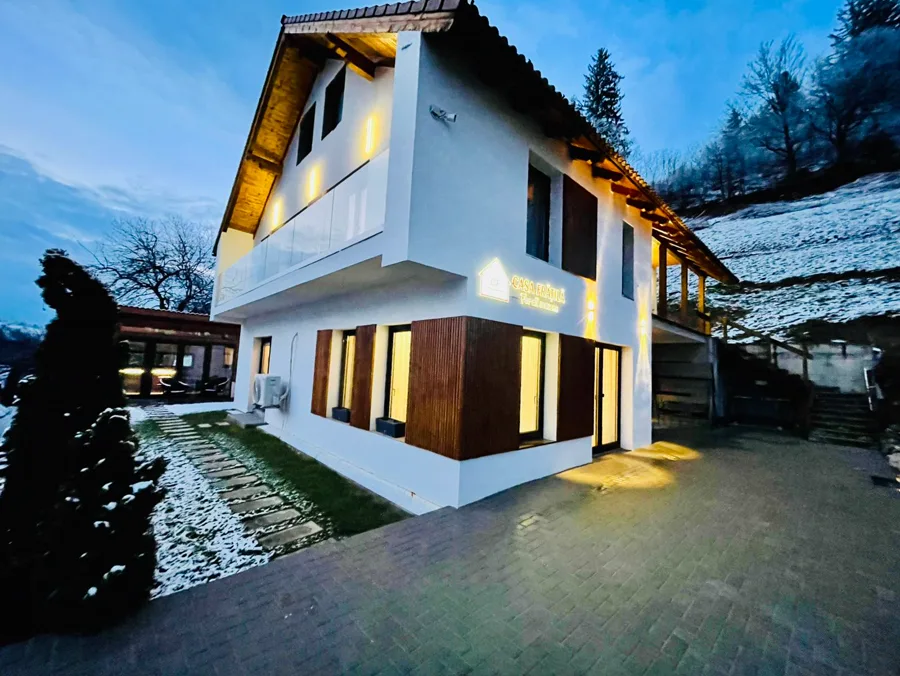 Casa Frătilă iarna — siglă luminoasă cu zăpadă pe dealuri